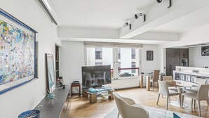 Un salon moderne doté d’un grand téléviseur, d’un coin repas avec des chaises, d’un espace cuisine et d’un balcon avec vue.