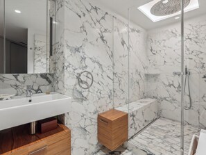 A modern bathroom with a marble backsplash, a glass-enclosed shower, and a wooden vanity. - Quai des Célestins  1bdr by B'Your Home (Paris)