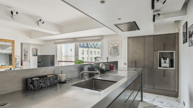 Une cuisine moderne dotée d’un grand îlot central, d’appareils électroménagers en acier inoxydable et offrant une vue sur la ville.