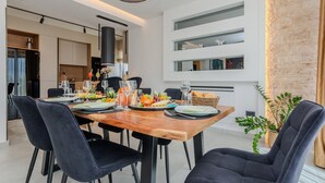 Un comedor moderno con una mesa de madera preparada para cuatro personas, rodeada de sillas negras.
