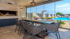 Una cocina moderna con una mesa de comedor de vidrio, sillas de piedra y vistas a una piscina.