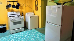 Cocina compacta con estufa a gas, lavadora y refrigerador.