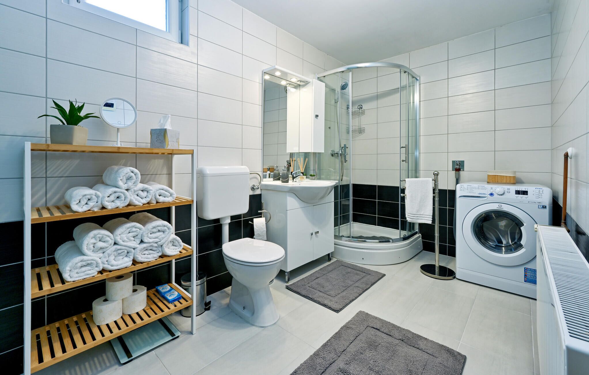 A modern bathroom with a toilet, sink, shower, and washing machine.