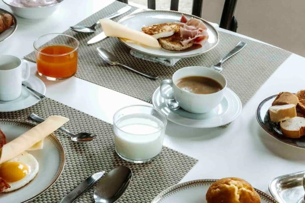 A breakfast setting with plates of food, a glass of orange juice, and a cup of coffee.