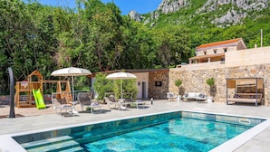 A swimming pool with a stone wall and a wooden play structure. - Awesome home in Bribir (Bribir)