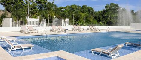 Una piscina con sillas de descanso y una fuente.