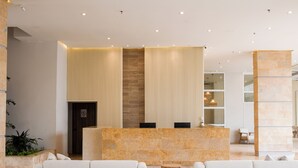A modern reception area with a marble reception desk, two sofas, and a vertical wooden panel.