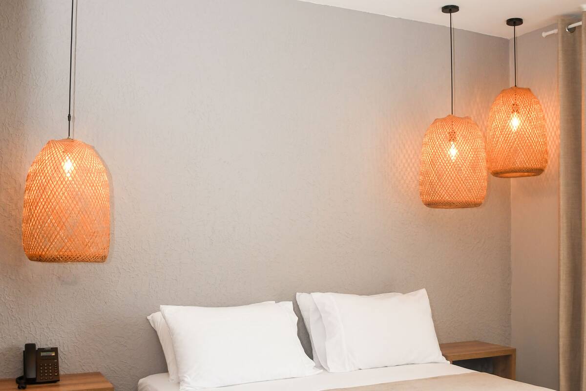 A bedroom with a bed, two bedside tables, and two hanging lamps.