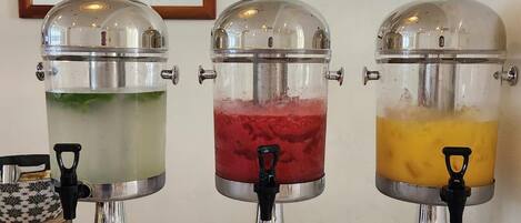 Three beverage dispensers with transparent containers and metallic bases, each with a black handle.