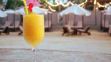 A cocktail with a straw and umbrella garnish on a table.