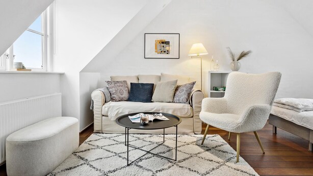 Un salón estilo loft con techo alto, un conjunto de sofás, una mesa de centro redonda y un ventanal grande.