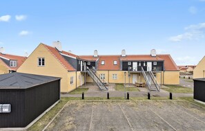 Un immeuble résidentiel doté de nombreux balcons, d’un escalier central et d’un espace de stationnement.