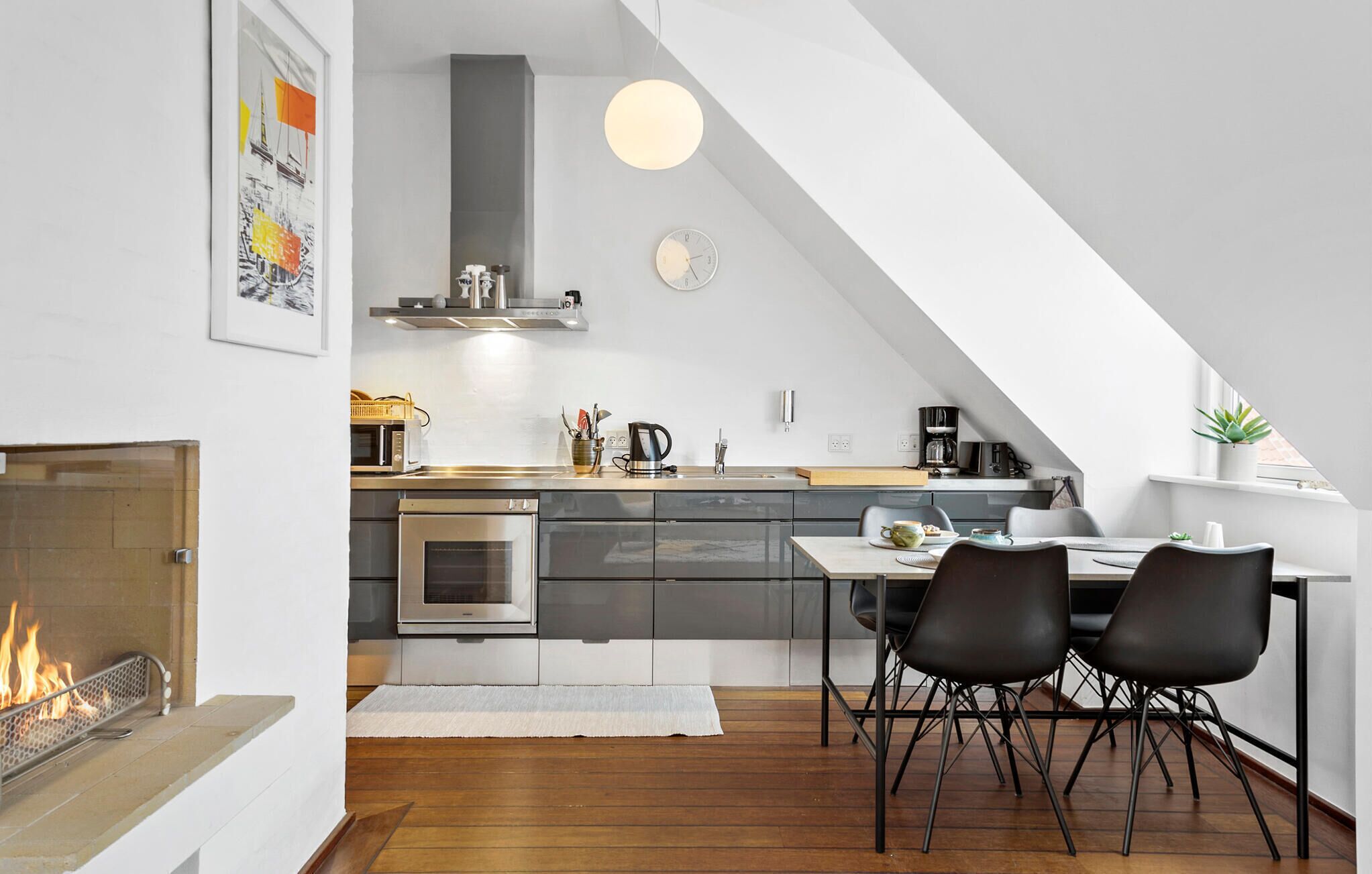 Una cocina moderna con comedor, chimenea y un reloj en la pared.