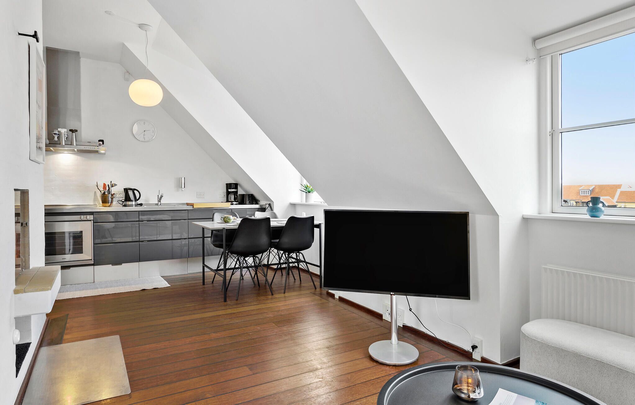 Un appartement moderne de style « loft » comprenant un coin repas, une kitchenette et une grande fenêtre.