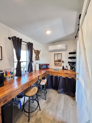 A compact kitchen with a wooden countertop, a microwave, a sink, and a refrigerator.