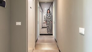 A hallway with a person in a striped outfit walking towards a door.