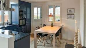Una cucina moderna con mobili scuri, un tavolo da pranzo in legno e una lampada a sospensione.