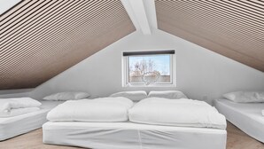 A modern attic bedroom with a sloped ceiling, a skylight, and a view of the outside.