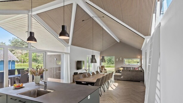 A spacious kitchen with a large island, modern pendant lighting, and a view of the outdoors.