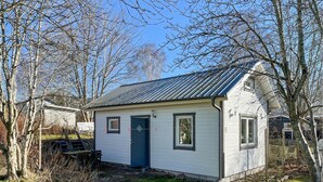 Une petite maison de plain-pied, avec un toit en métal, un revêtement extérieur blanc et une porte bleu foncé.