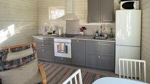 Une cuisine de taille réduite avec des meubles gris, un réfrigérateur blanc, un four à micro-ondes et une machine à café.