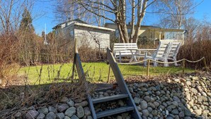 Une structure en pierre avec une échelle en bois menant à un espace agrémenté de bancs et de chaises blanches.