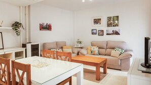 Uma sala moderna com área de jantar, sofá, mesa de centro e televisão.