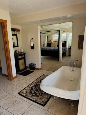 A bedroom with a canopy bed, a bathroom with a bathtub, and a view of a snowy landscape.
