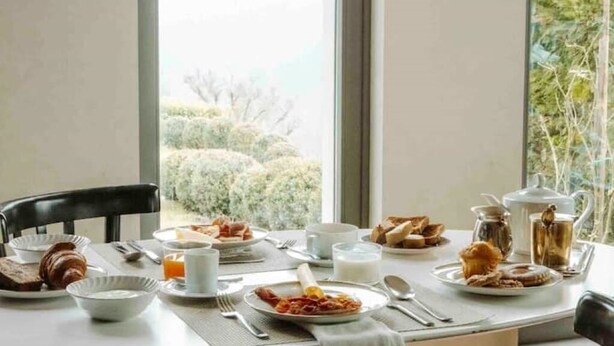 A breakfast table set with plates of food, including croissants, toast, and pastries, and a pitcher of milk. - Tenuta Moncarlino - Camera Luce (Piemonte)