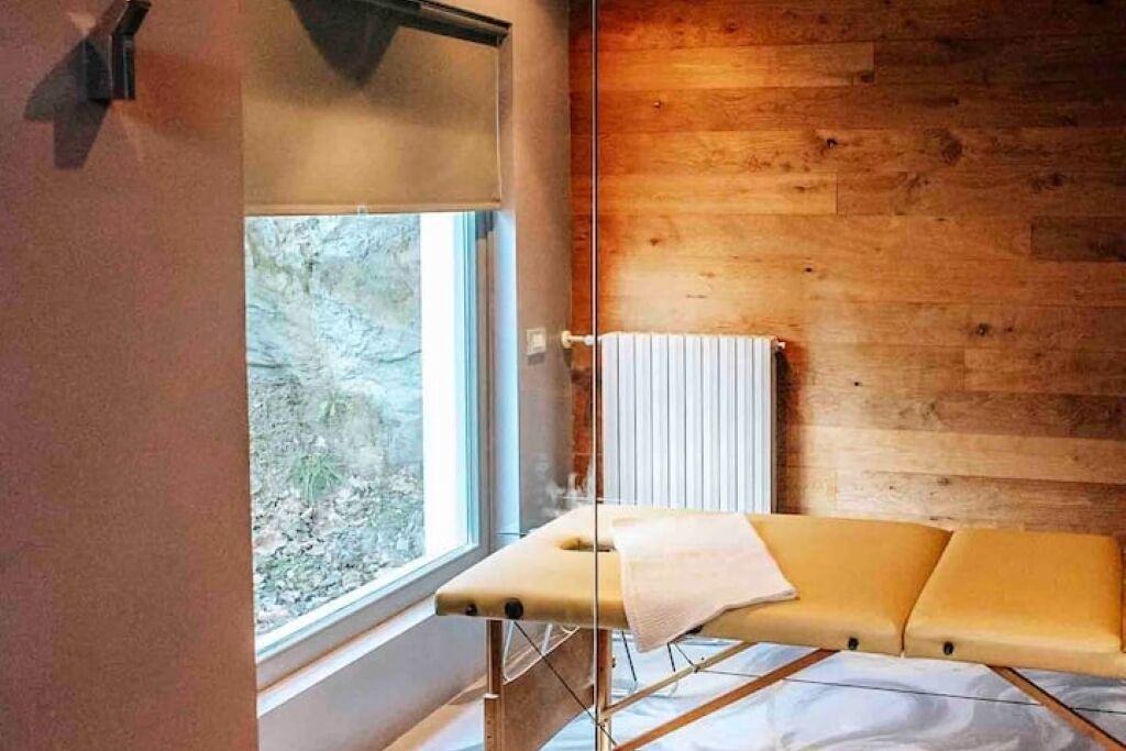 Una habitación con pared de madera, una ventana y una camilla de masaje.
