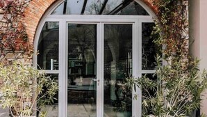 A large arched doorway with a glass door, flanked by potted plants. - Tenuta Moncarlino - Camera Luce (Piemonte)