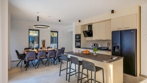 Una cucina moderna con isola centrale, elettrodomestici integrati e zona pranzo con un'ampia finestra.
