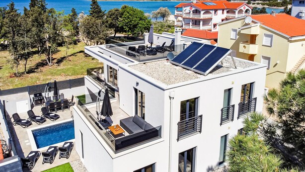 Un edificio moderno con piscina sul tetto, pannelli solari e vista sul mare.
