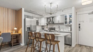 Une cuisine moderne dotée d’un îlot central, d’appareils électroménagers en acier inoxydable et d’un mur d’accent en bois.