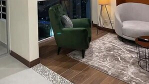 A room with a large window, a green armchair, a white armchair, a floor lamp, and a patterned rug. - Sky View Penthouse Costa Rica (Empalme)