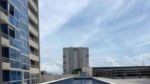 A swimming pool with a clear blue water surface, surrounded by modern buildings with balconies. - Sky View Penthouse Costa Rica (Empalme)