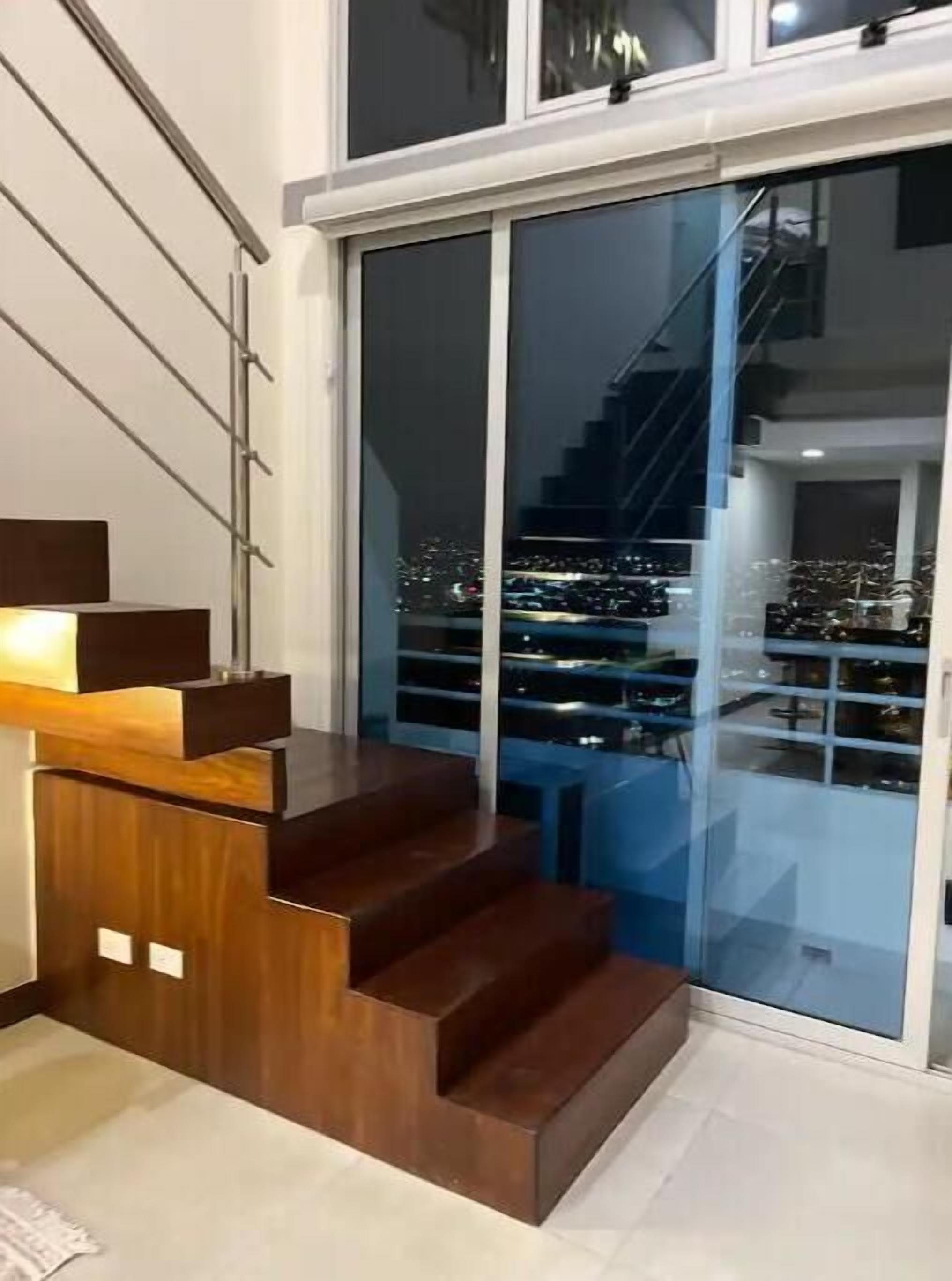 A modern staircase with a glass door leading to a balcony with a city view. - Sky View Penthouse Costa Rica (Empalme)