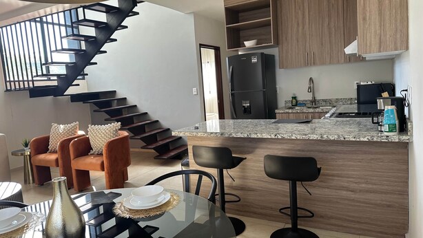 A modern kitchen with a built-in refrigerator, wooden cabinets, and a granite countertop.