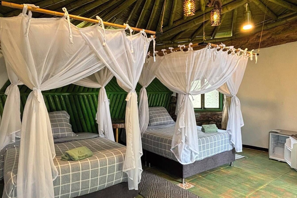 Ein Zimmer mit zwei Betten, jeweils mit Baldachin, und einem kleinen Tisch dazwischen.