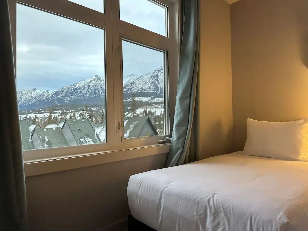 Une chambre d’hôtel avec un lit et une fenêtre donnant sur des montagnes enneigées.