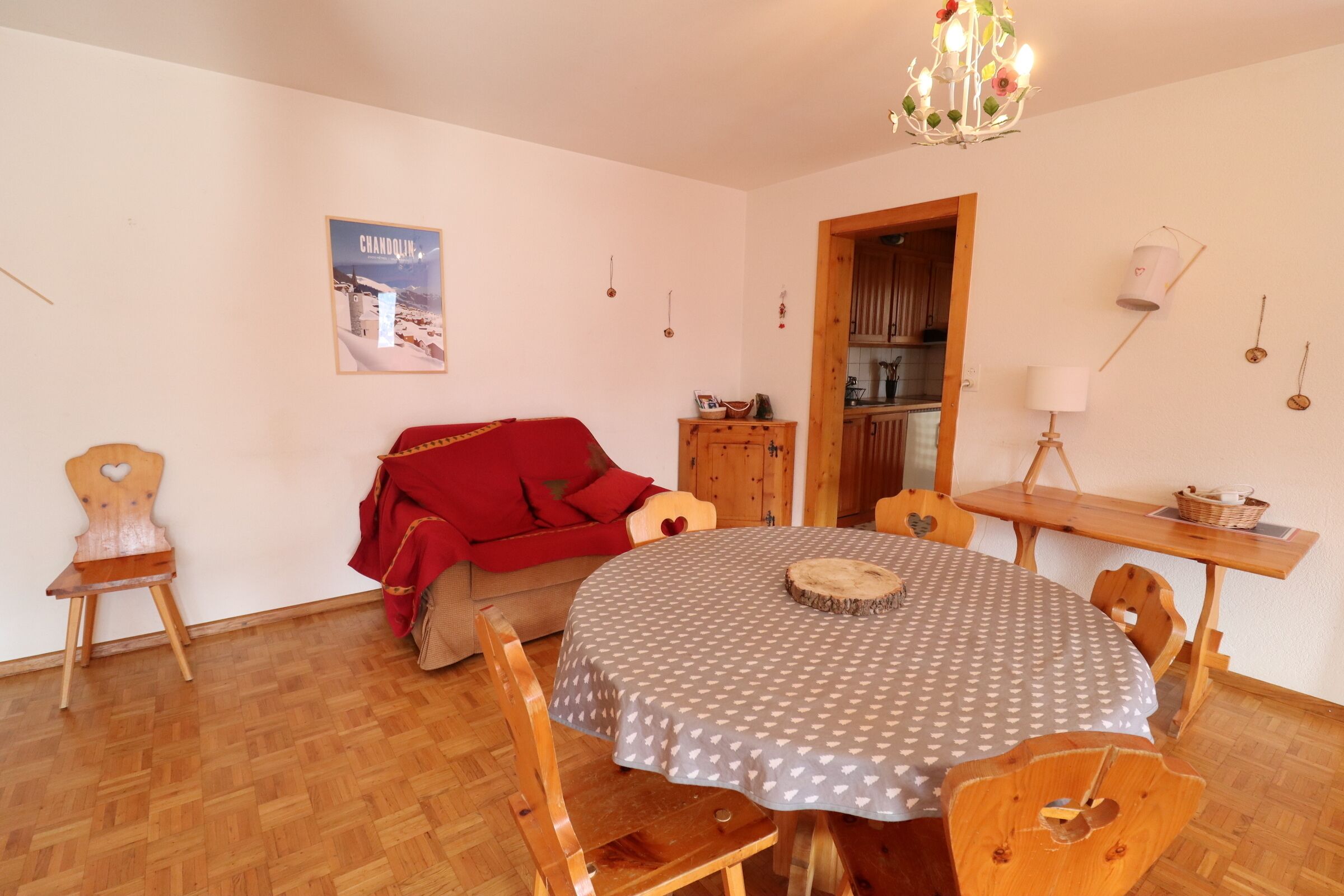 Ein gemütliches Wohnzimmer mit einem runden Tisch, Holzstühlen, einem roten Sofa und einer Deckenleuchte.