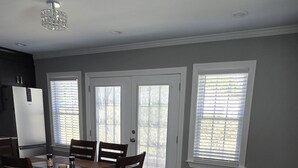 A dining area with a wooden table and chairs, a refrigerator, and a chandelier. - Deluxe! New Apt Loft Near Downtown – Ready for Families and Business Travelers. (Raleigh)