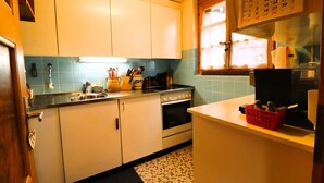 A kitchen with white cabinets, a stove, and a sink. There is a calendar on the wall and a window with blinds. - Charming detached cottage for up to 5 people. It has a good location close to a shuttle bus stop tha (St-Luc)