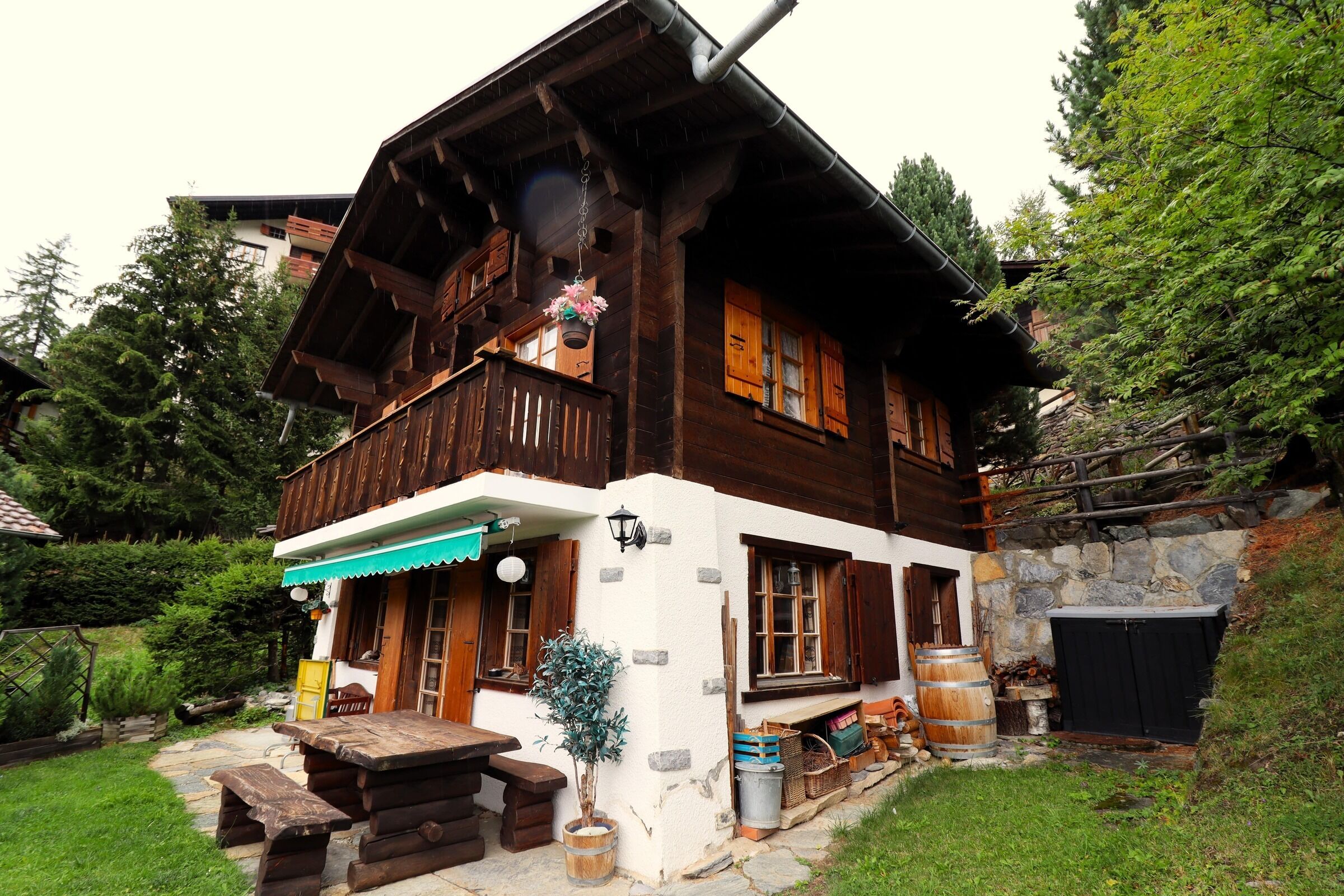 Un chalet en bois doté d’un balcon, de murs en pierre et d’un escalier en pierre menant à l’entrée.