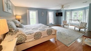 Une chambre à coucher avec un lit, une chaise, une télévision et une fenêtre.