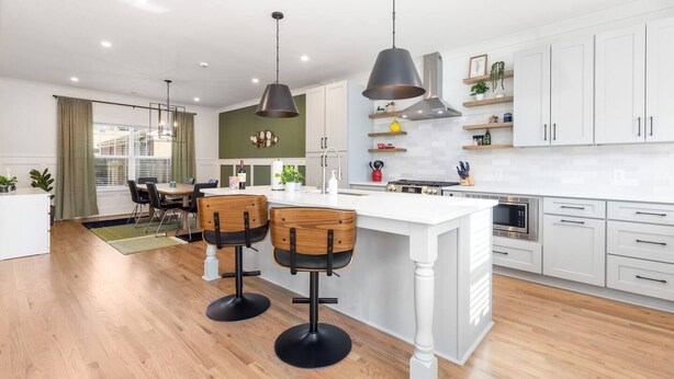 A modern kitchen with white cabinets, a central island, and bar stools. - Epic Group Stay: 2 Homes + Hot Tubs + Yard Games (Charlotte)