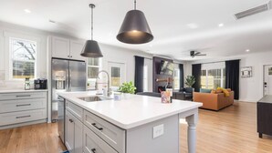 A modern kitchen with a central island, stainless steel appliances, and pendant lighting. - Epic Group Stay: 2 Homes + Hot Tubs + Yard Games (Charlotte)