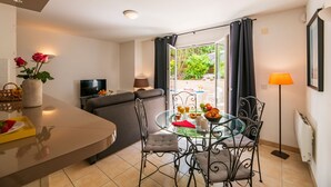 A modern living room with a glass dining table, comfortable seating, a flat-screen TV, and a view of the outdoors. - À 400m de la plage | T2 avec terrasse ou balcon (Arcachon)