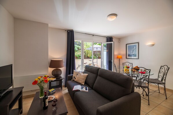 A modern living room with a sofa, coffee table, and a dining area with chairs and a table. - À 400m de la plage | T2 avec terrasse ou balcon (Arcachon)