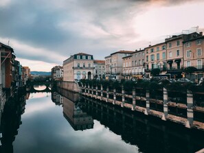 A canal with buildings on either side, a bridge, and a clear sky.